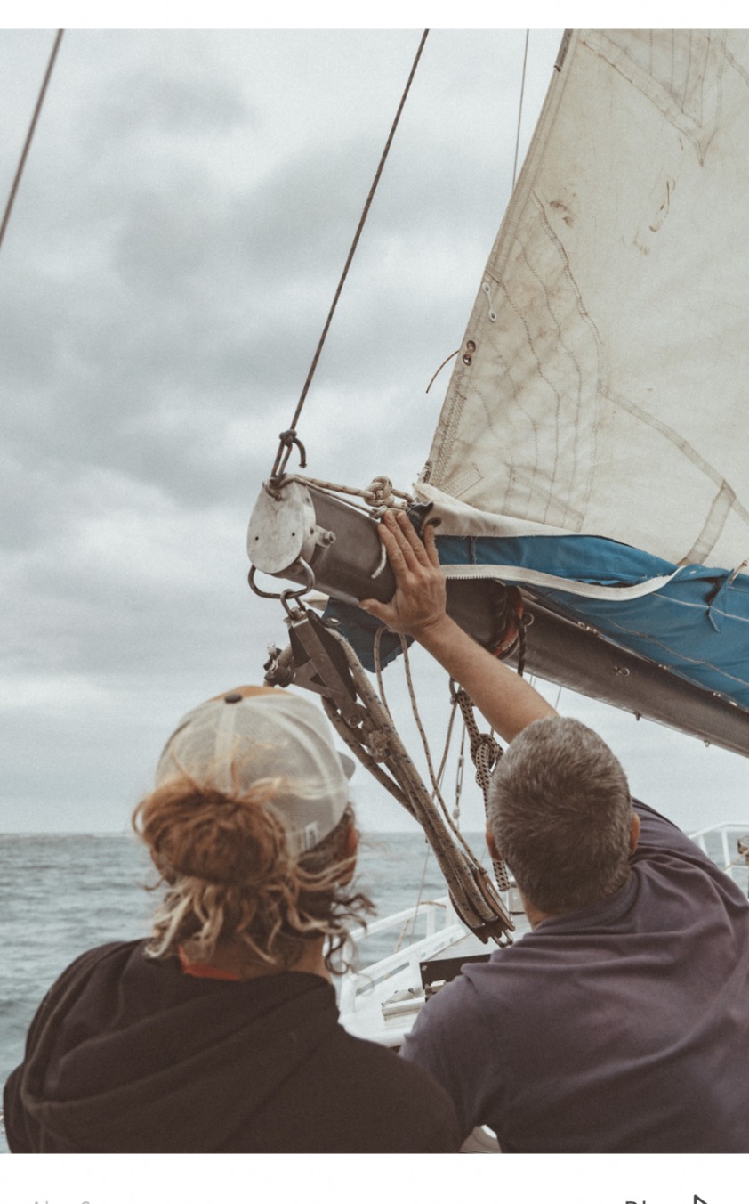Crew adjusting the sail rigging while out at sea