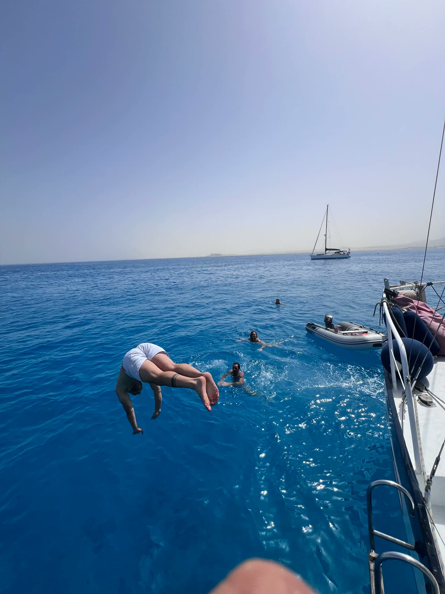 Guest diving from the side of the yacht into deep blue water