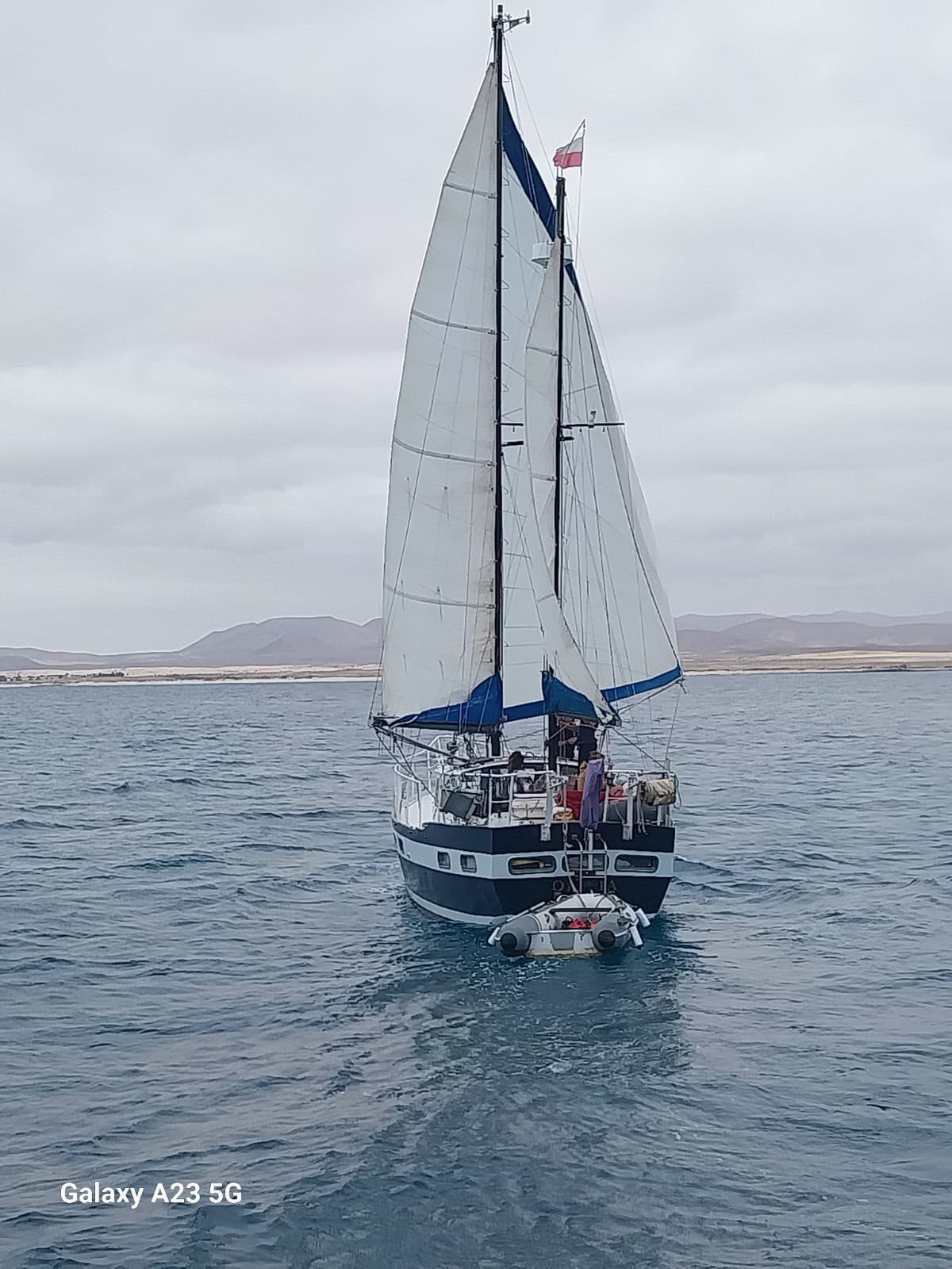 Swimmers in crystal-clear turquoise water beside a sailing yacht near Lobos