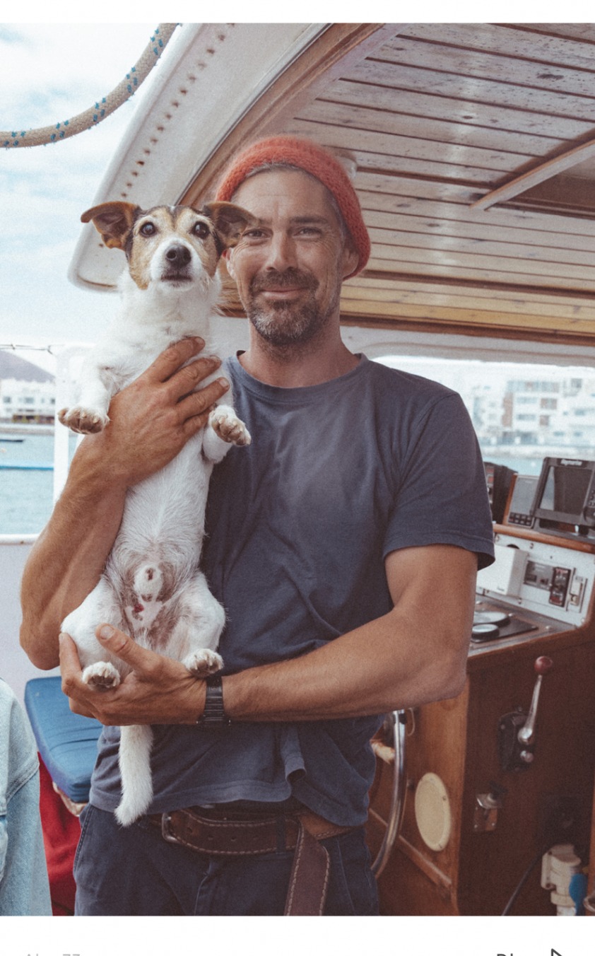 Skipper holding a small dog aboard Sailing Olivia