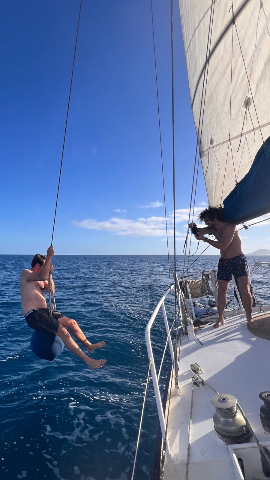 Guest swinging from a halyard rope over the open Atlantic